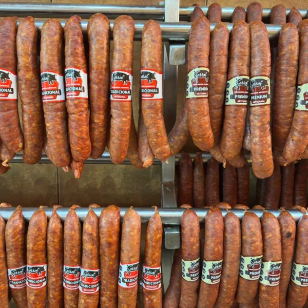 Longanizas Tradicional y Premium Serrot colgadas lado a lado en la sala de ahumado